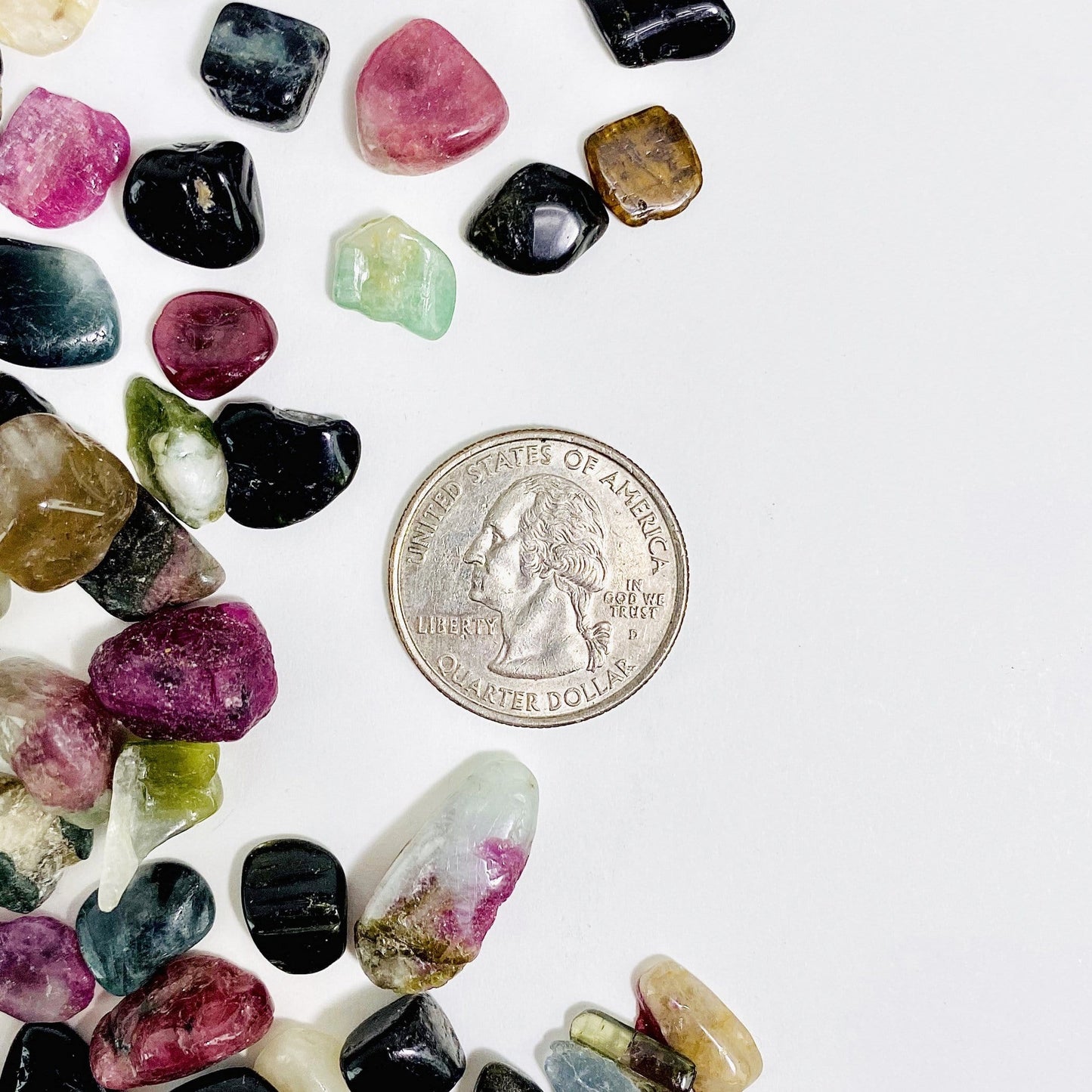 Watermelon Tourmaline Chips next to a quarter for size reference