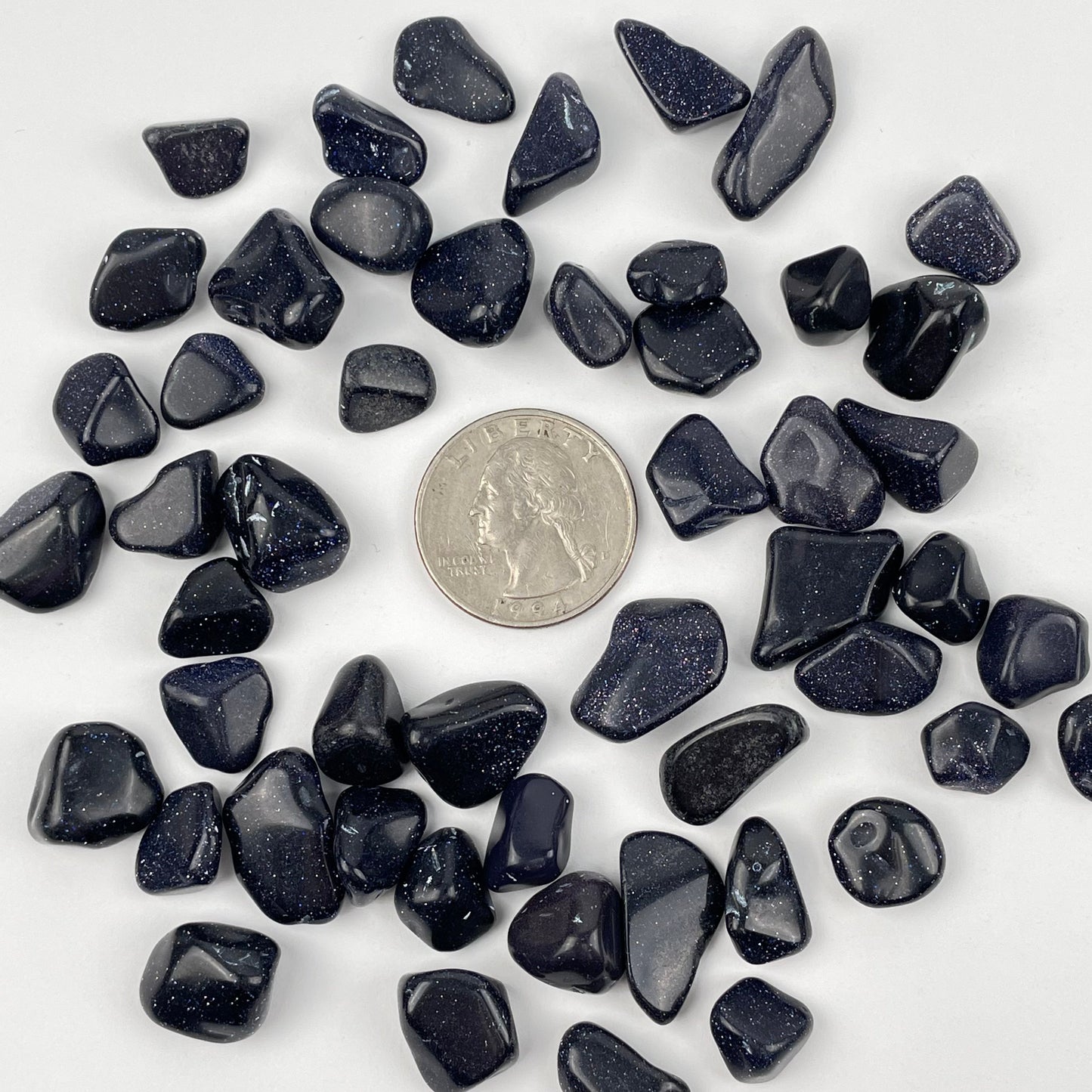 Blue Goldstone Tumbled Chips next to a quarter for size reference