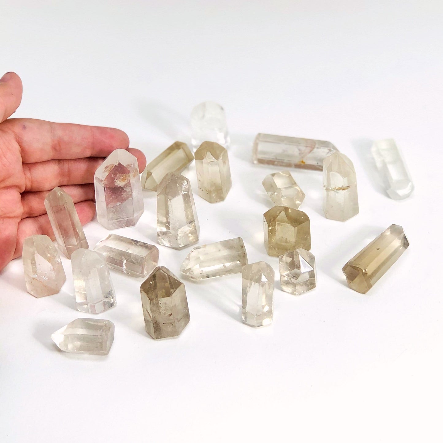 Crystal Quartz Polished Points laid out with a hand for size reference