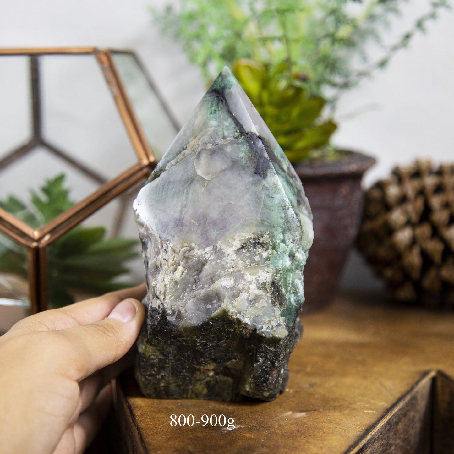 Semi Polished point Emerald Stone in hand showing the weight of 800 to 900g on white background