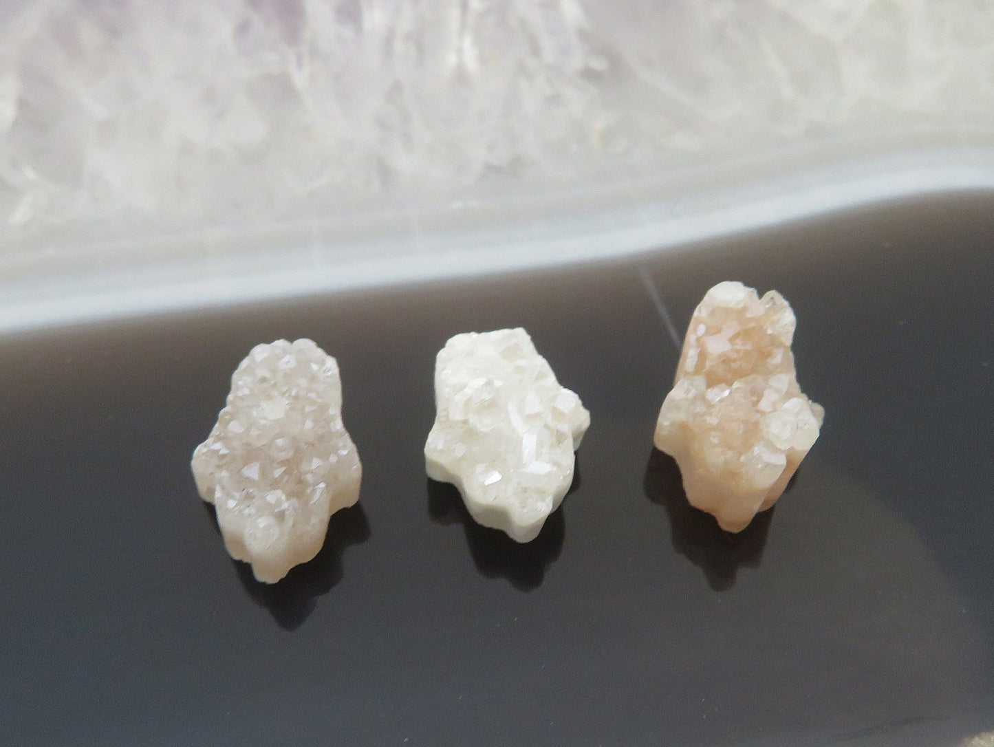 head drilled hamsa bead titanium druzy in assorted color shown against light backgrounds