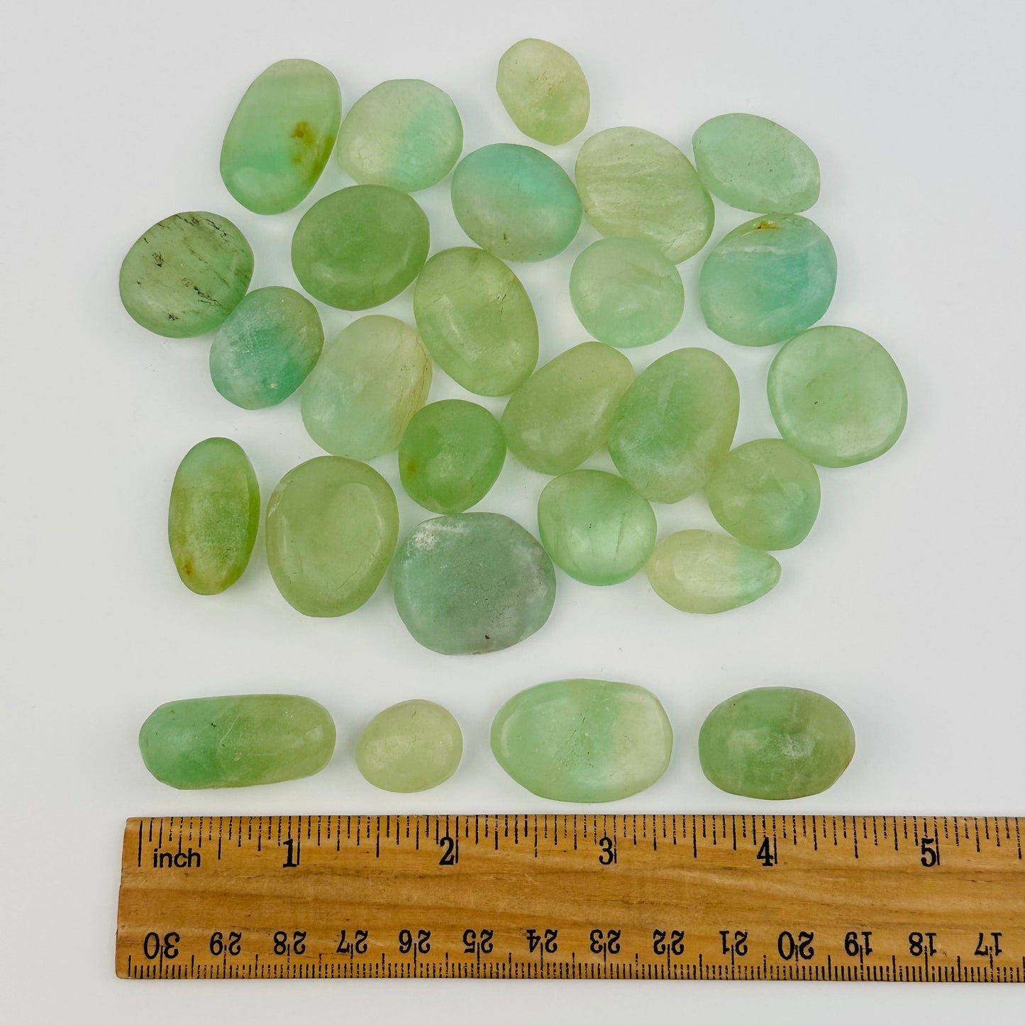 tumbled stones displayed next to a ruler for size reference