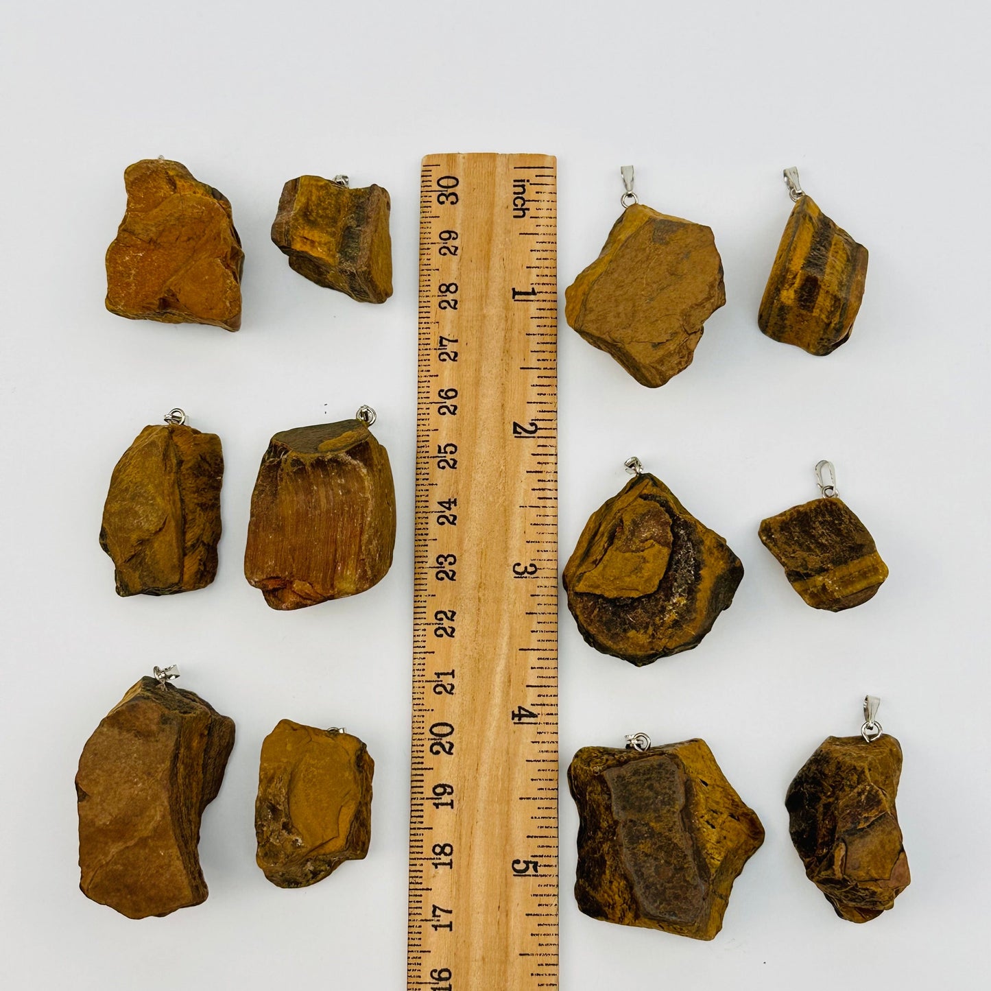 tiger eye pendants displayed next to a ruler for size reference