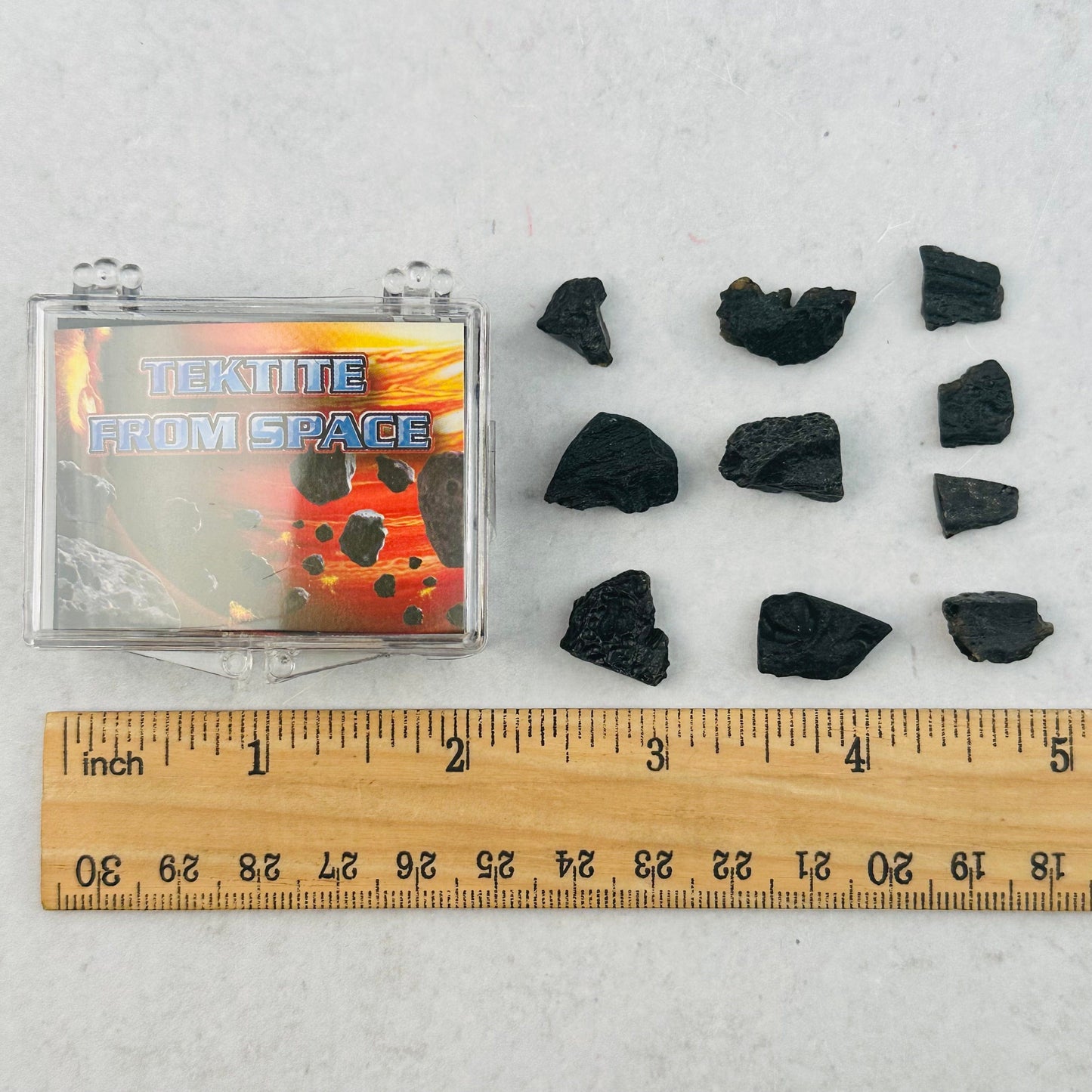 tektite next to a ruler for size reference