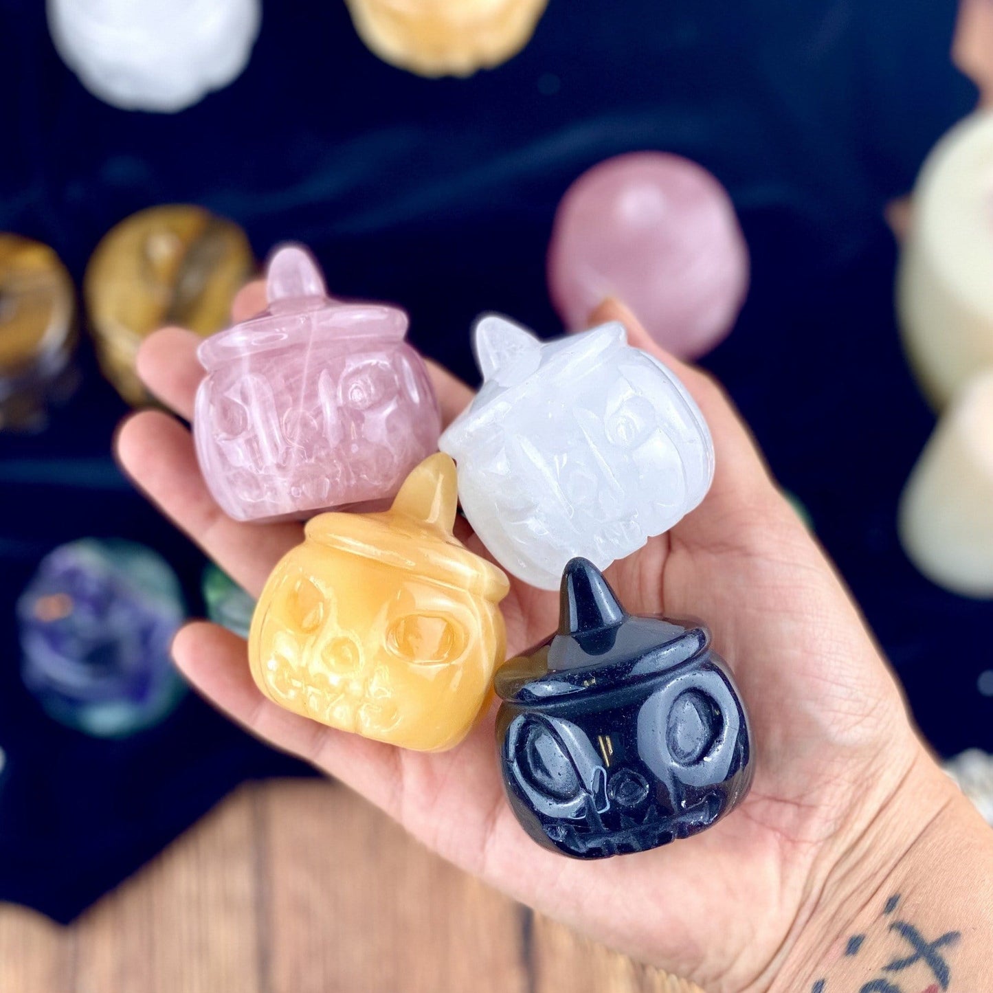 Rose Quartz, Crystal Quartz, Orange Citrine and Black Obsidian Carved Pumpkin Jack-o'-lantern Gemstones held in a woman's hand.