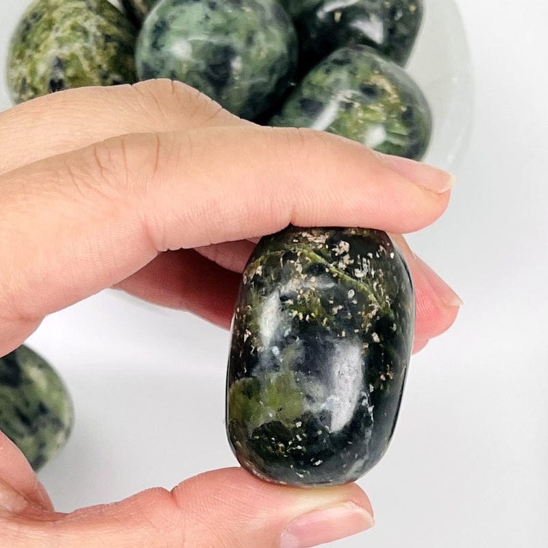 nephrite tumbled stone in hand for size reference