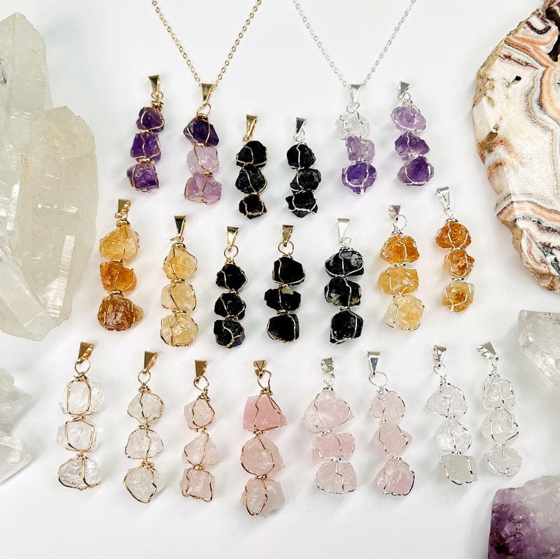 all pendants in gold and silver displayed next to each other to show the differences in the stone types