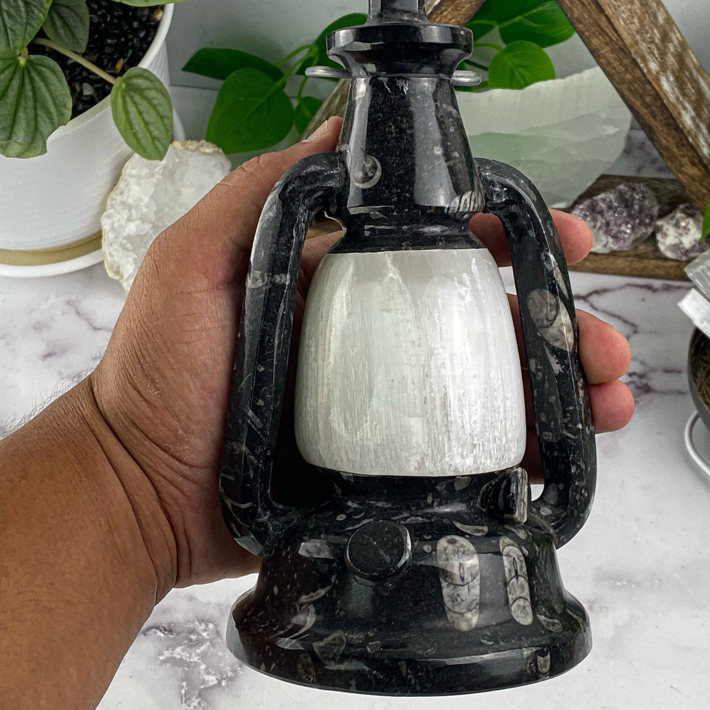 hand holding up Orthoceras and Selenite Lamp with decorations in the background