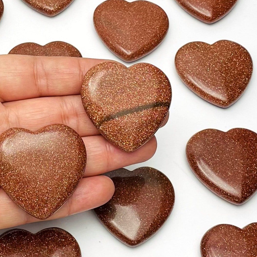 multiple heart shaped goldstone on a hand for reference size