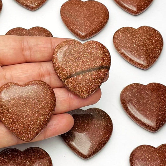 multiple heart shaped goldstone on a hand for reference size