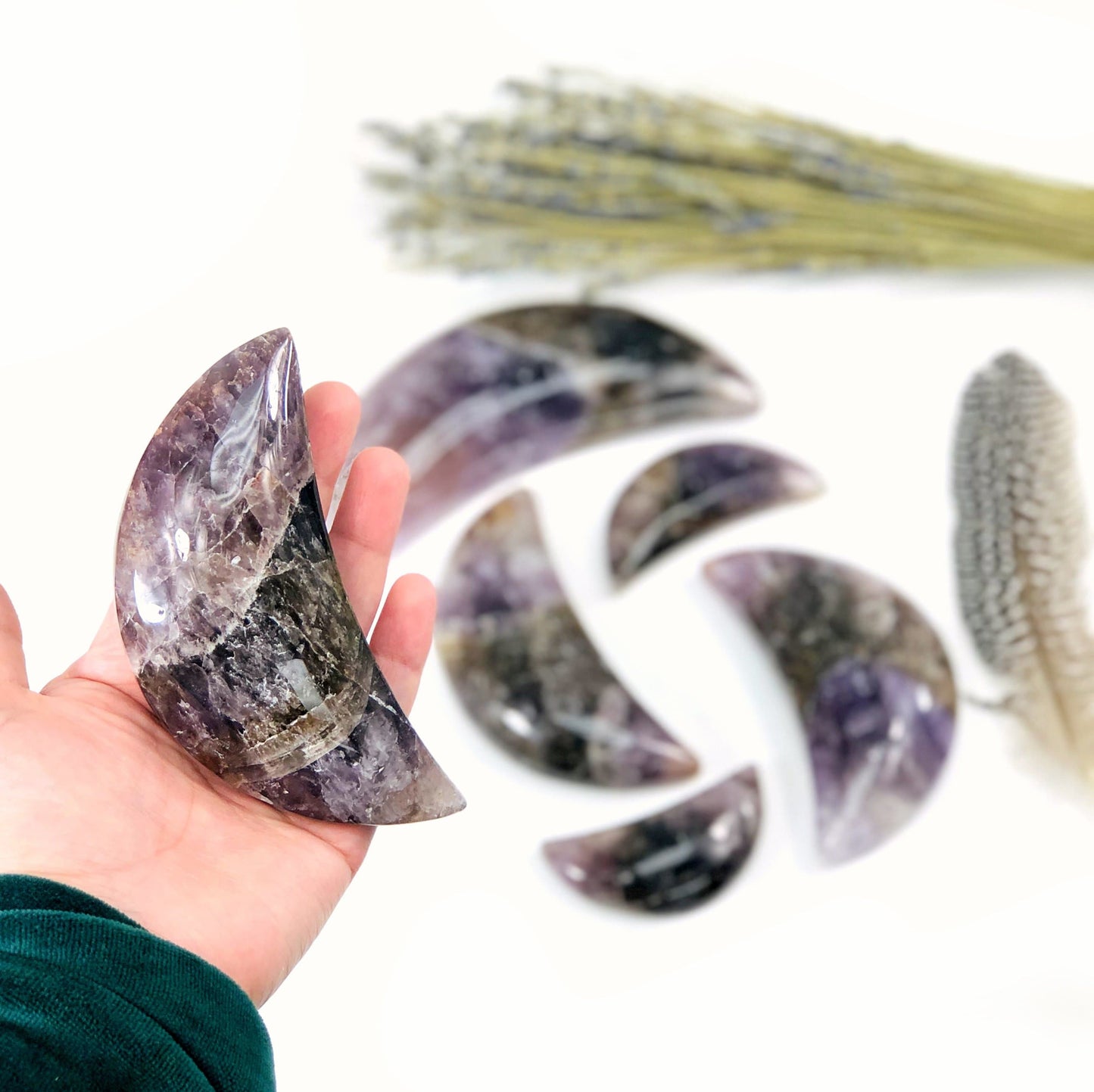 seven minerals in one polished moon in hand for size reference with others in background