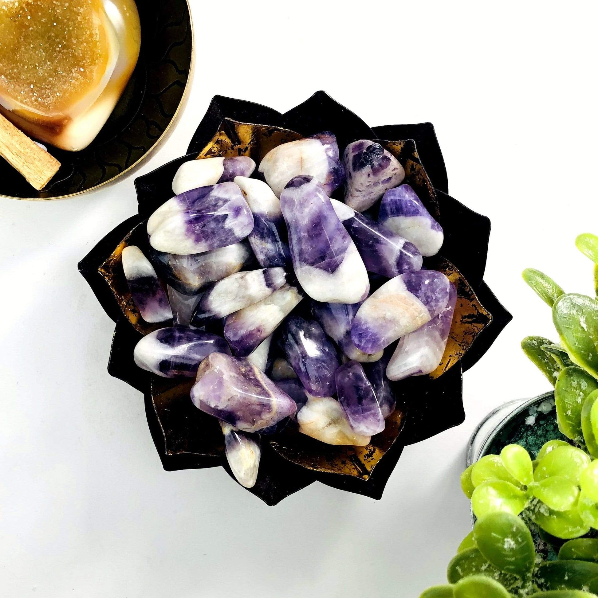 A gold bowl holding Chevron Amethyst Tumbled Gemstones