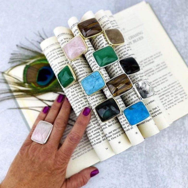 book with folded pages displaying multiple stone rings in different stones with hand wearing one