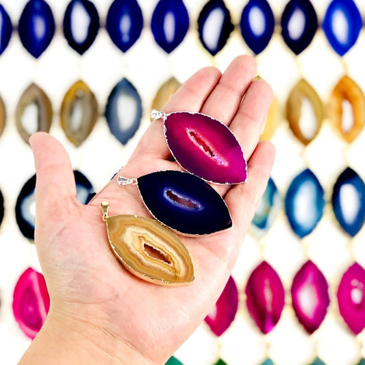 Three Agate Druzy Pendants Extra Grade Agates Marquise Shape in a hand. Multiple pendants in the background. 