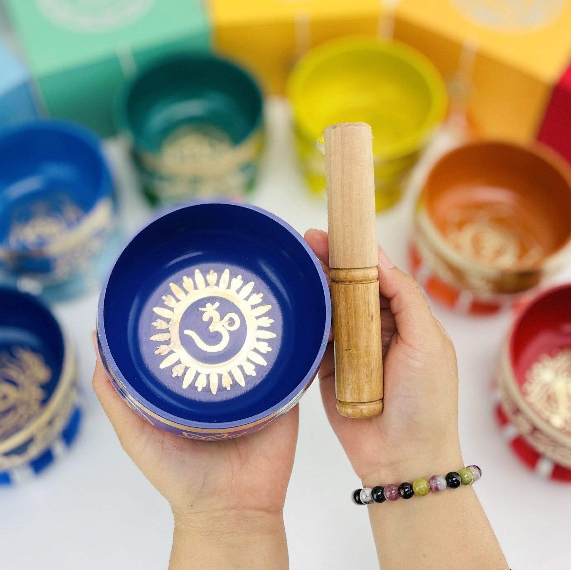 Deep purple colored Brass Tibetan Chakra Singing Bowl and mallot in a hand 