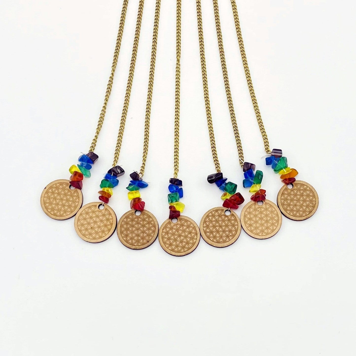 Mini engraved wood circles Each decorated with chakra colored tumbled glass accents on white background.