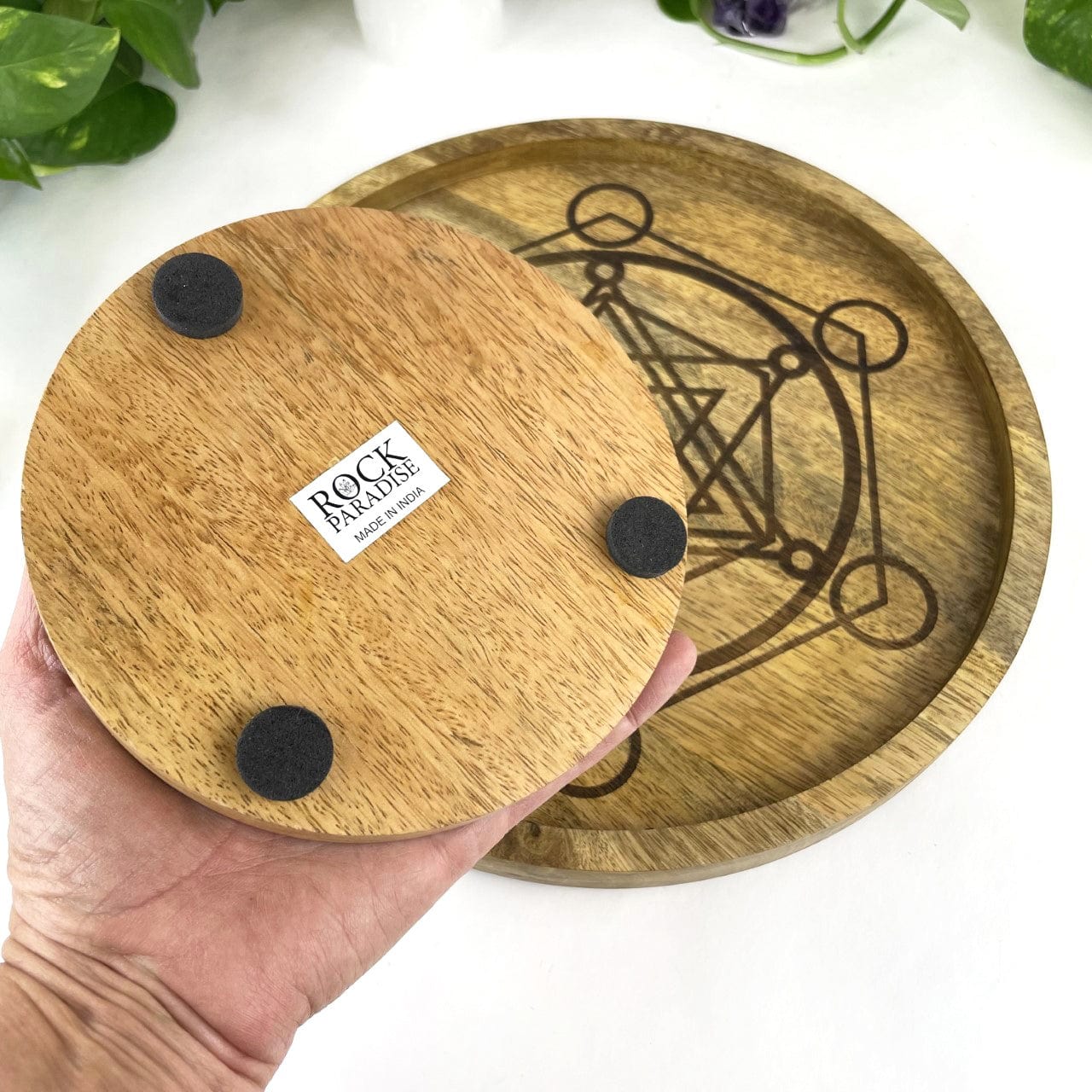 Backside of small tray demonstrating it has 3 black round felt pads and a rock paradise sticker with made in India on the back.  Large tray is visible in the background