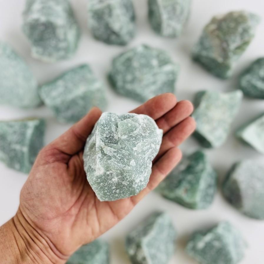 green quartz rough stone in hand for size reference 
