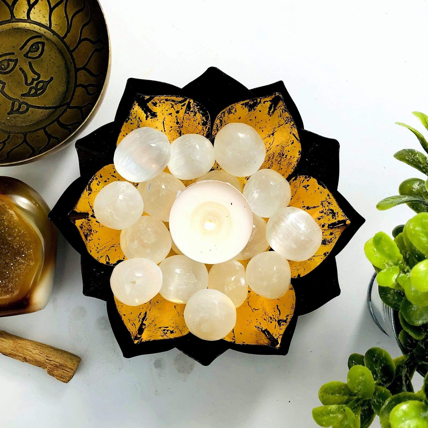 Selenite Tumbled Freeform stones in a bowl on display with a candle