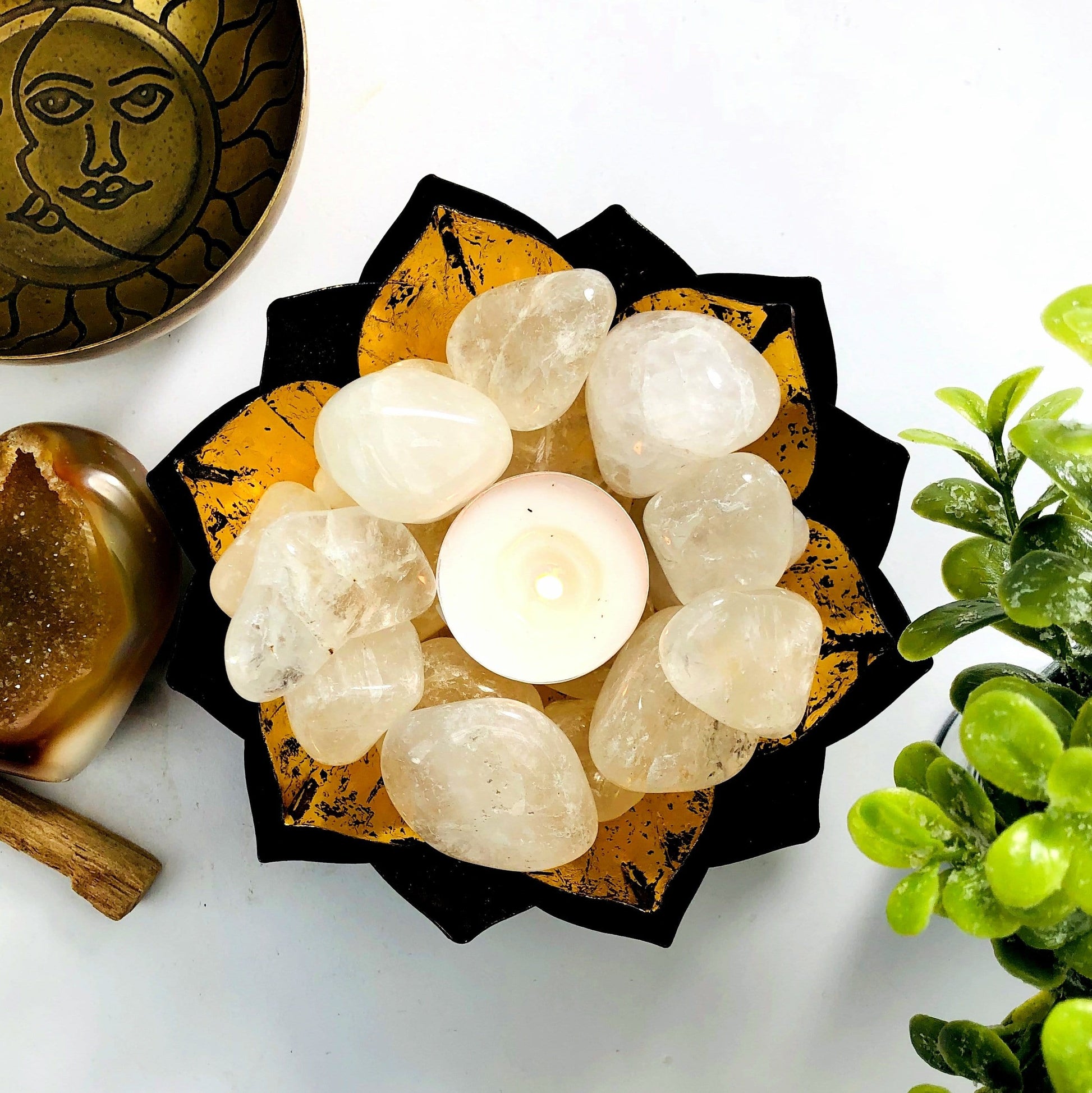 Crystal Quartz tumbled stones in a lotus bowl with a tealight candle lit in the center.