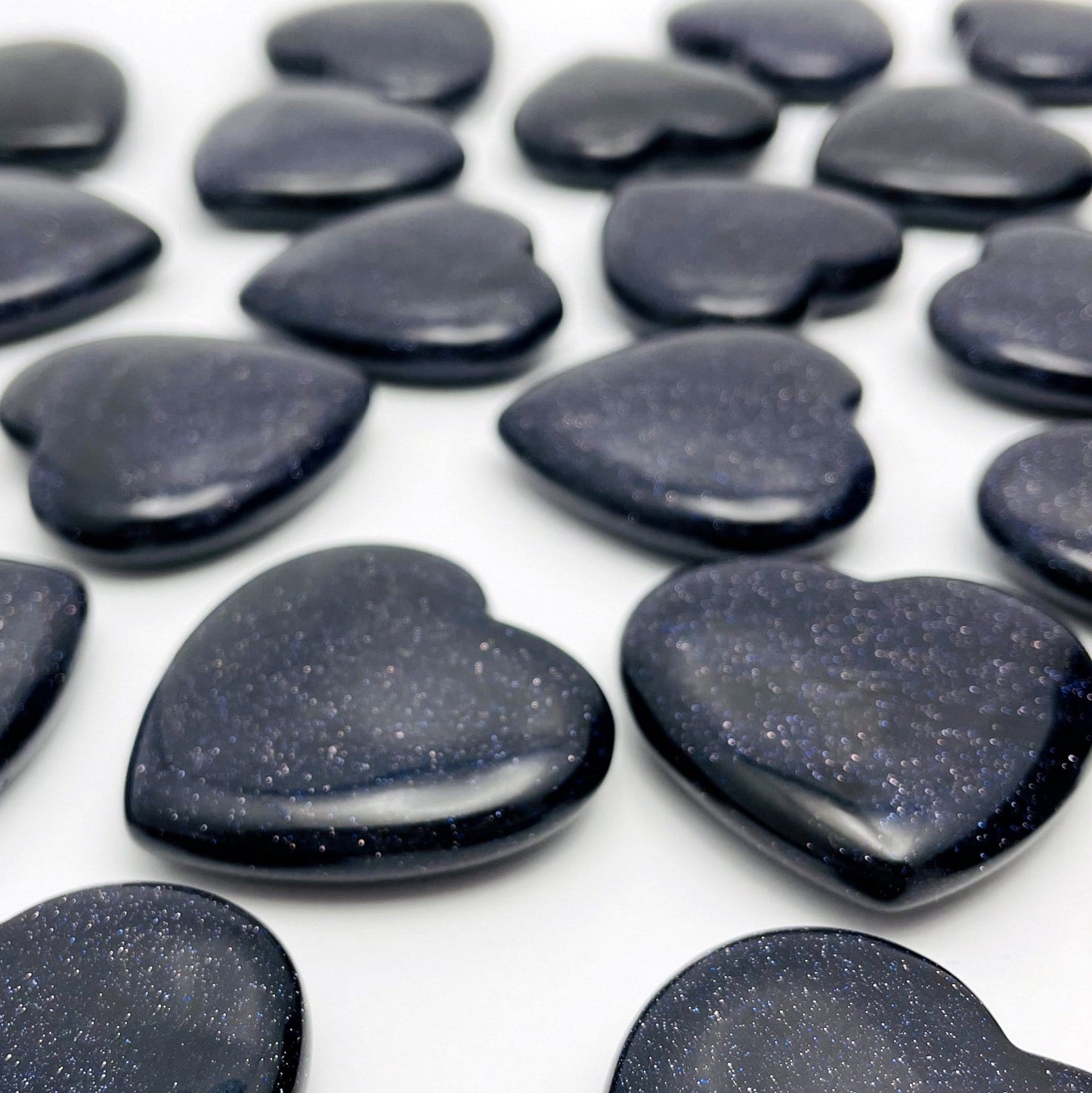 Close Up of Dark Blue Goldstone Hearts on White Background.