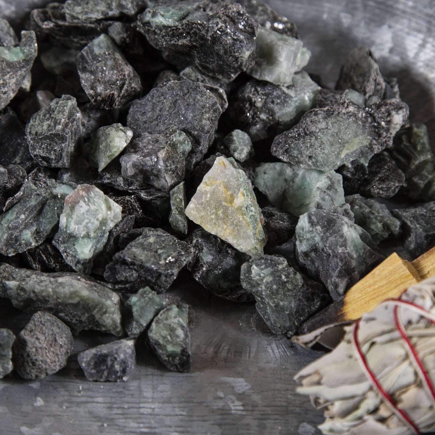 Close up of Emerald Rough Stones next to a buddle of sage.