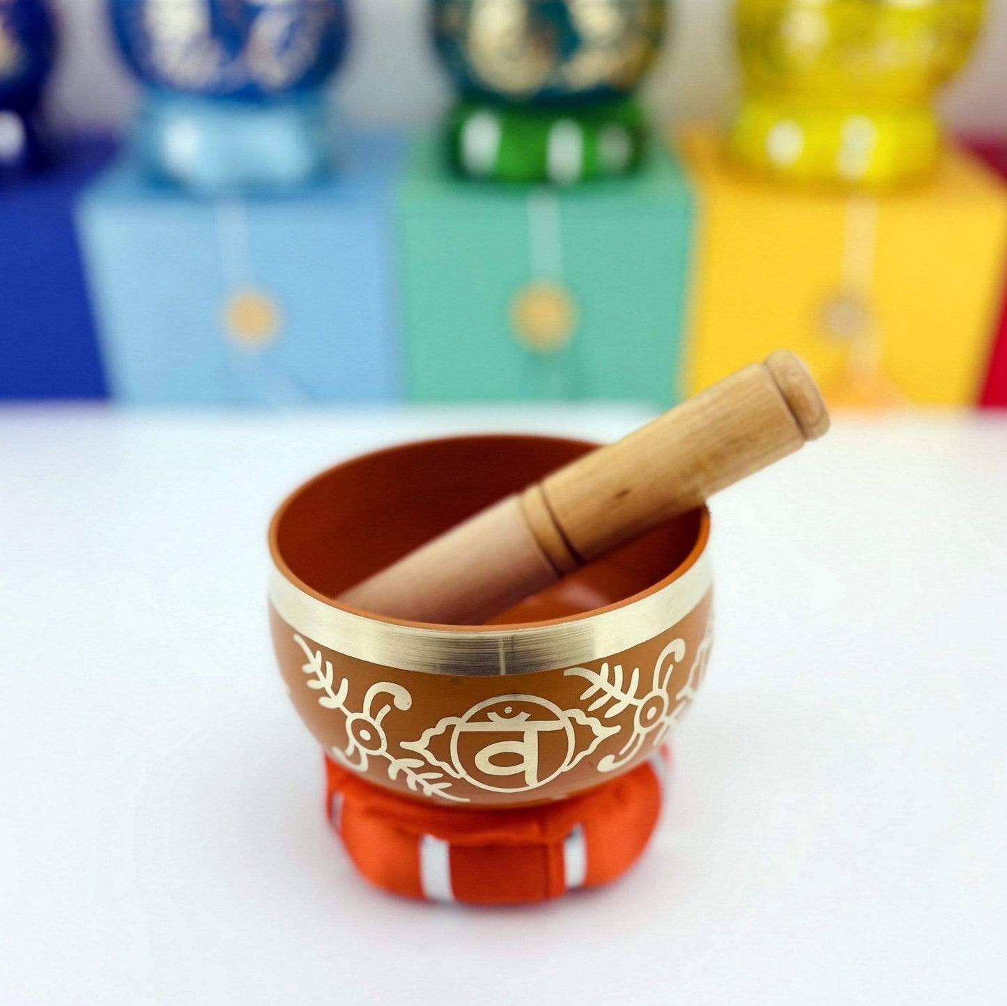 Orange Brass Tibetan Chakra Singing Bowl on pillow with a mallot