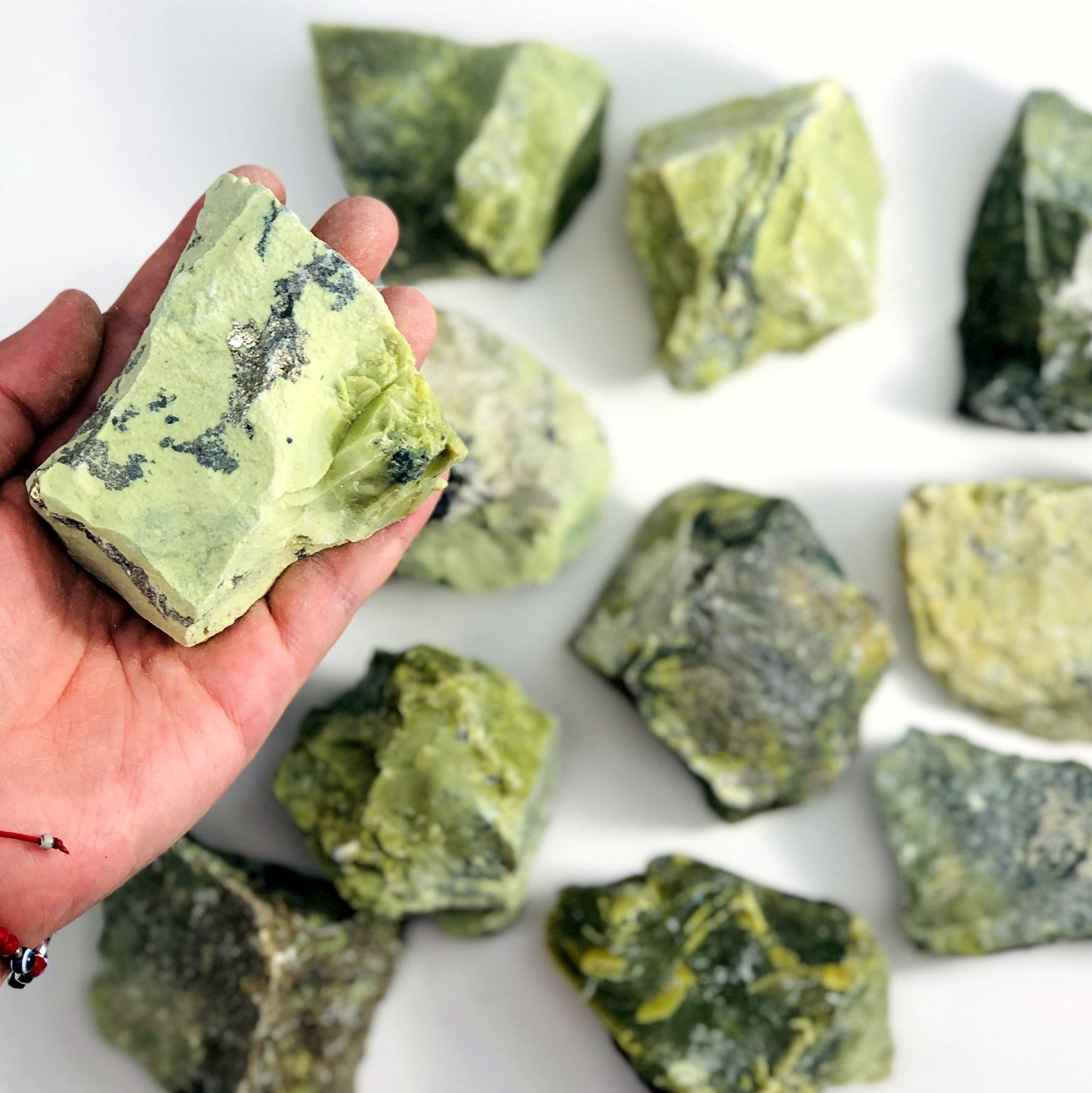 one serpentine rough stone in hand for size reference with others in background