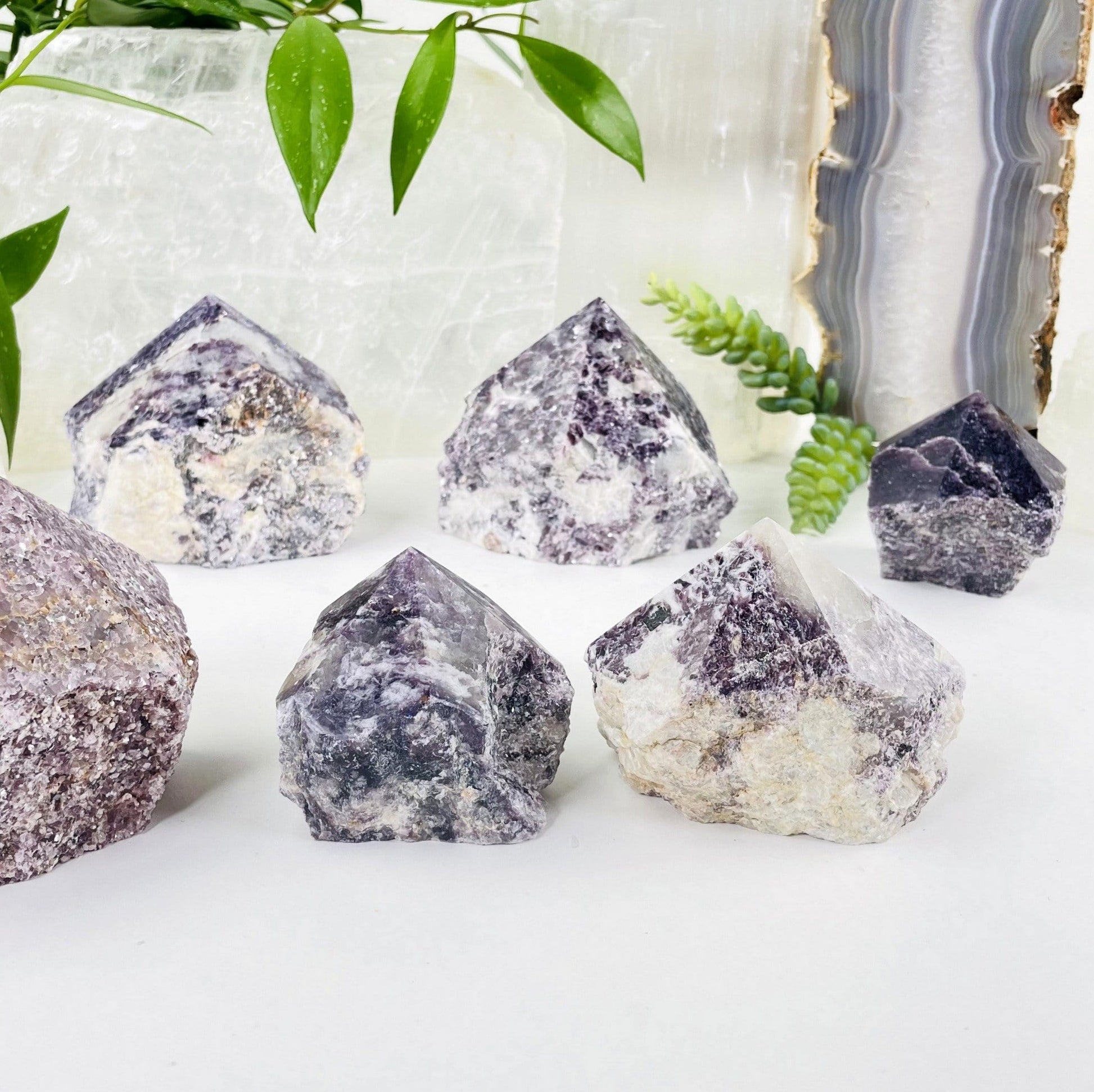 lepidolite semi polished point with decorations in the background