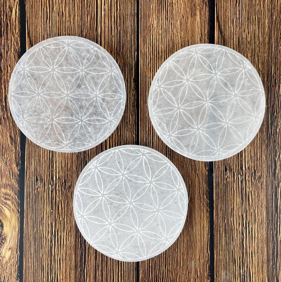 overhead close up of three selenite round plates engraved with flower of life for engraving details and possible variations