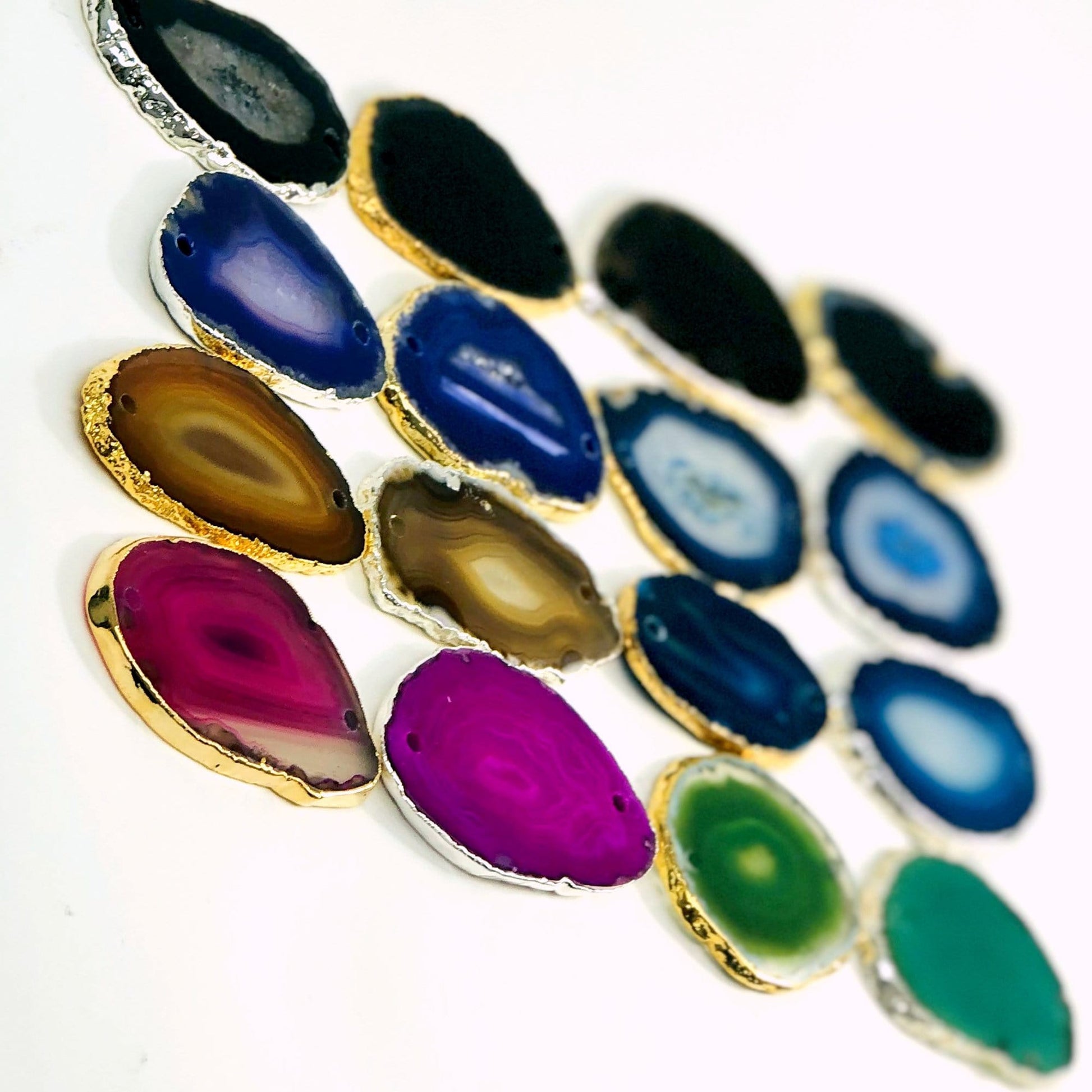 This picture is showing all the variety of colors we have available for our agate slices plated edge double drilled,  on a white background.