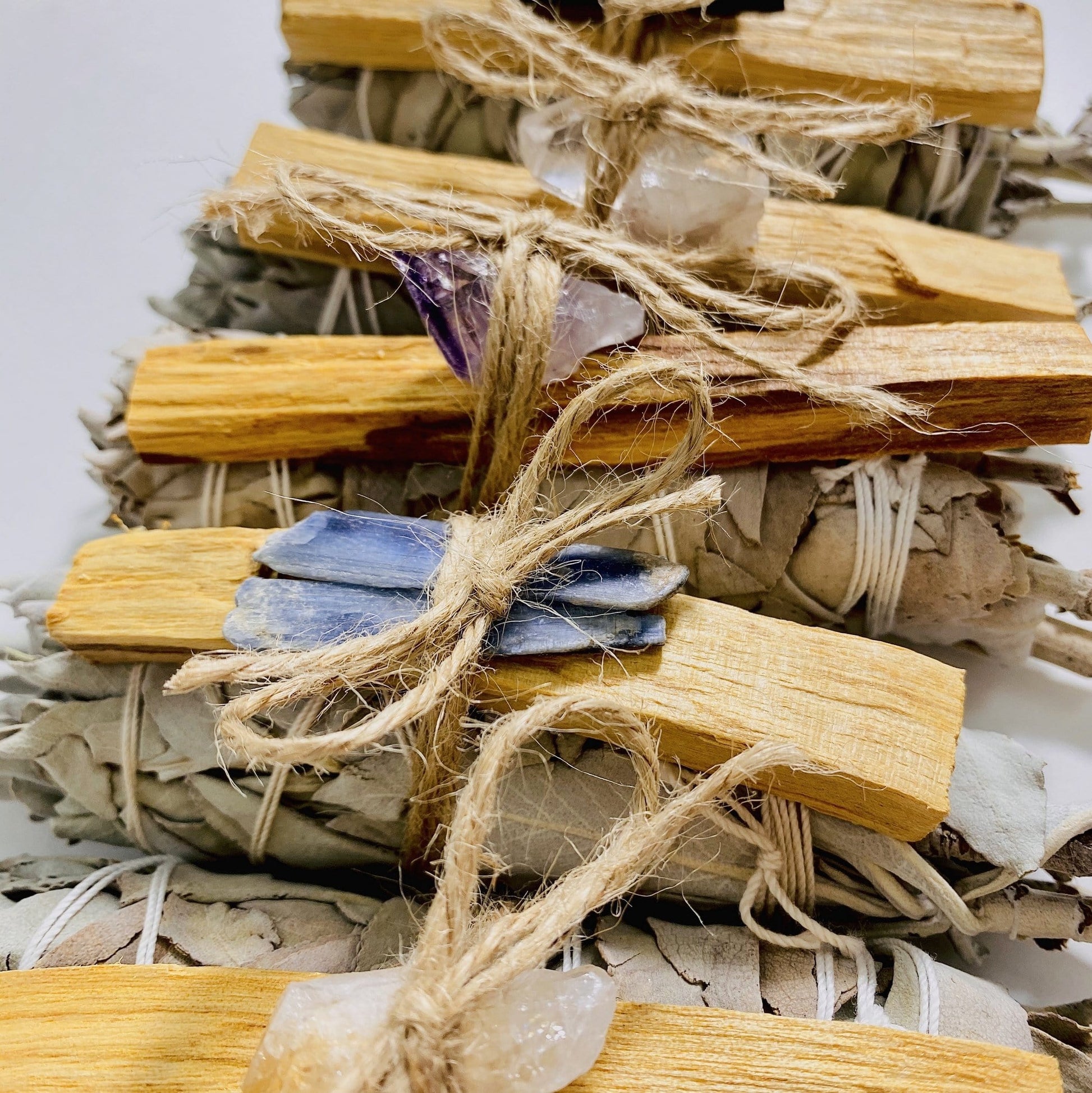 side view of sage bundle palo santo with assorted stone
