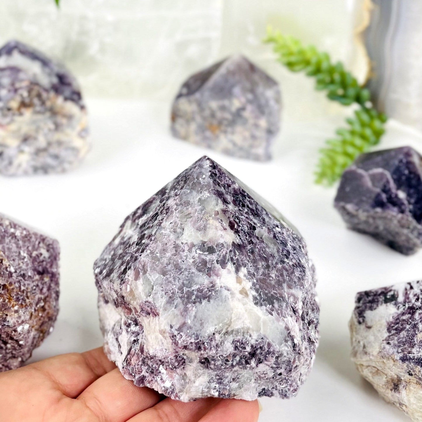 lepidolite semi polished point with decorations in the background