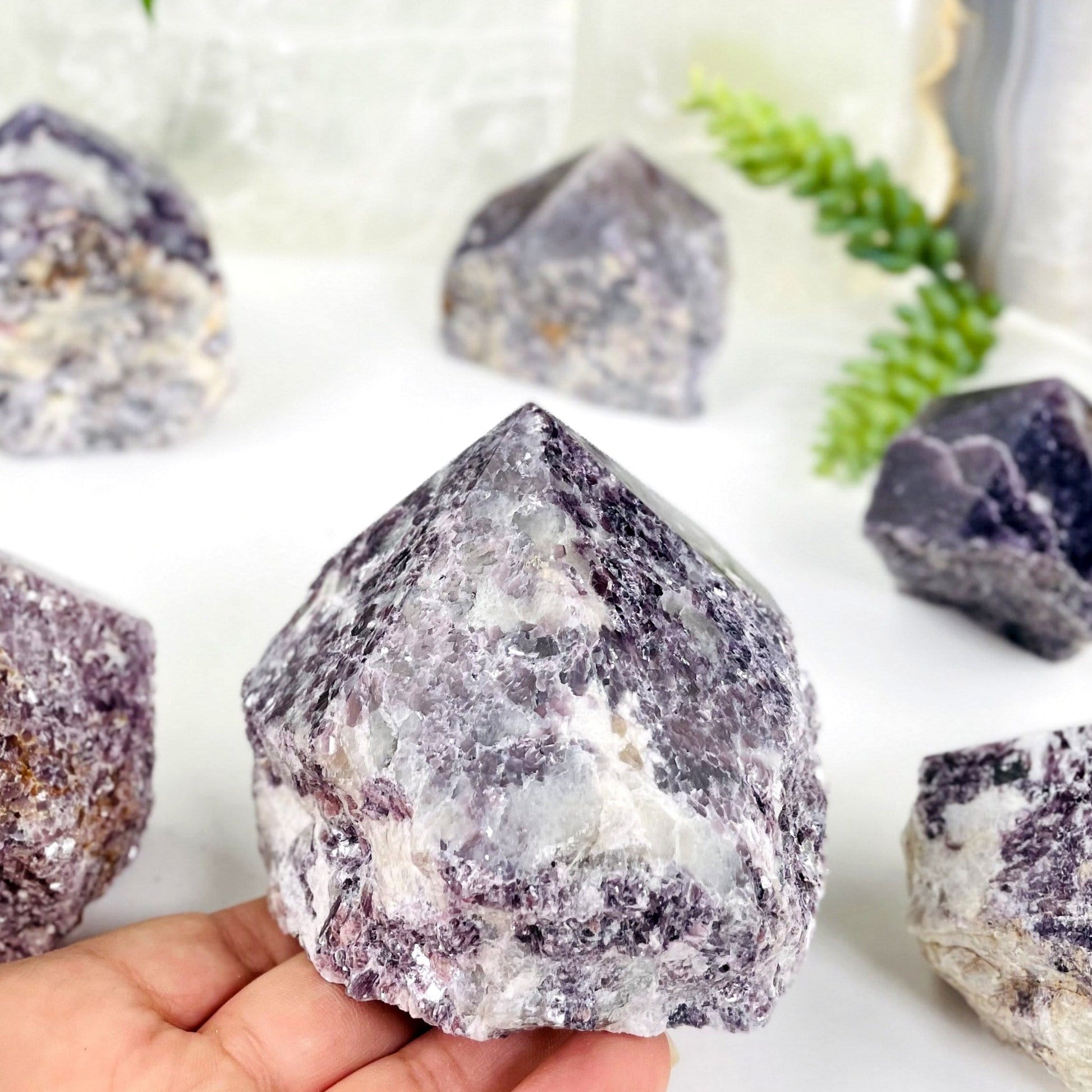 lepidolite semi polished point with decorations in the background