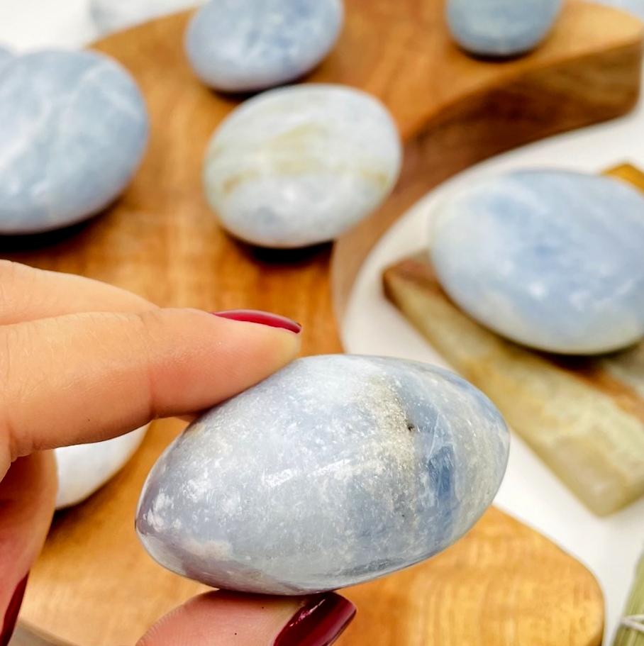 side view of blue calcite palm stone in a hand