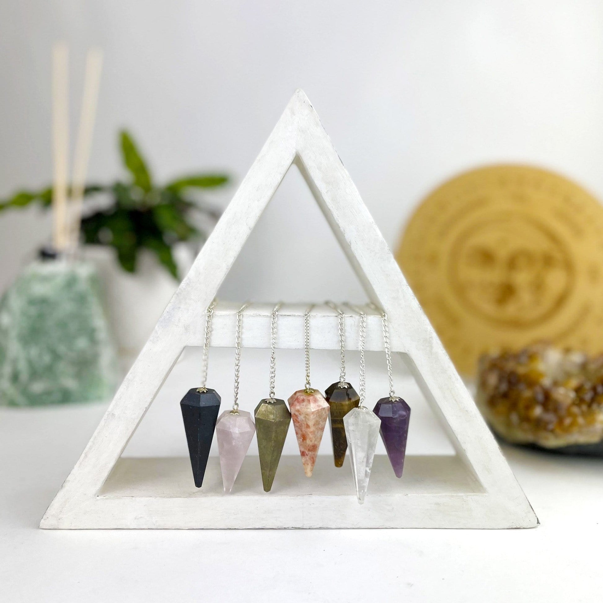 various colors of crystal pendulums hanging on silver chains 