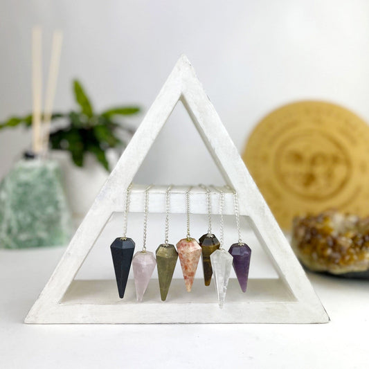 various colors of crystal pendulums hanging on silver chains 
