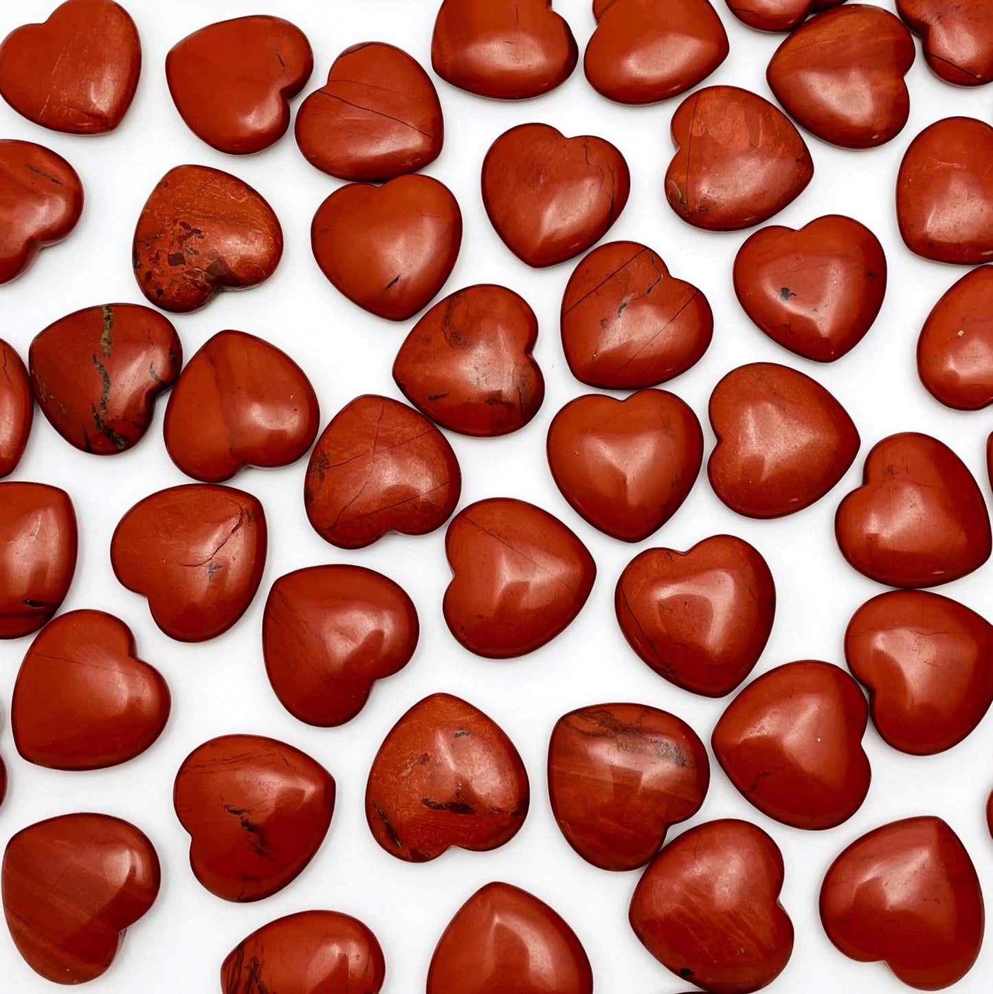 Red Jasper Heart Shaped Stones scattered on white background