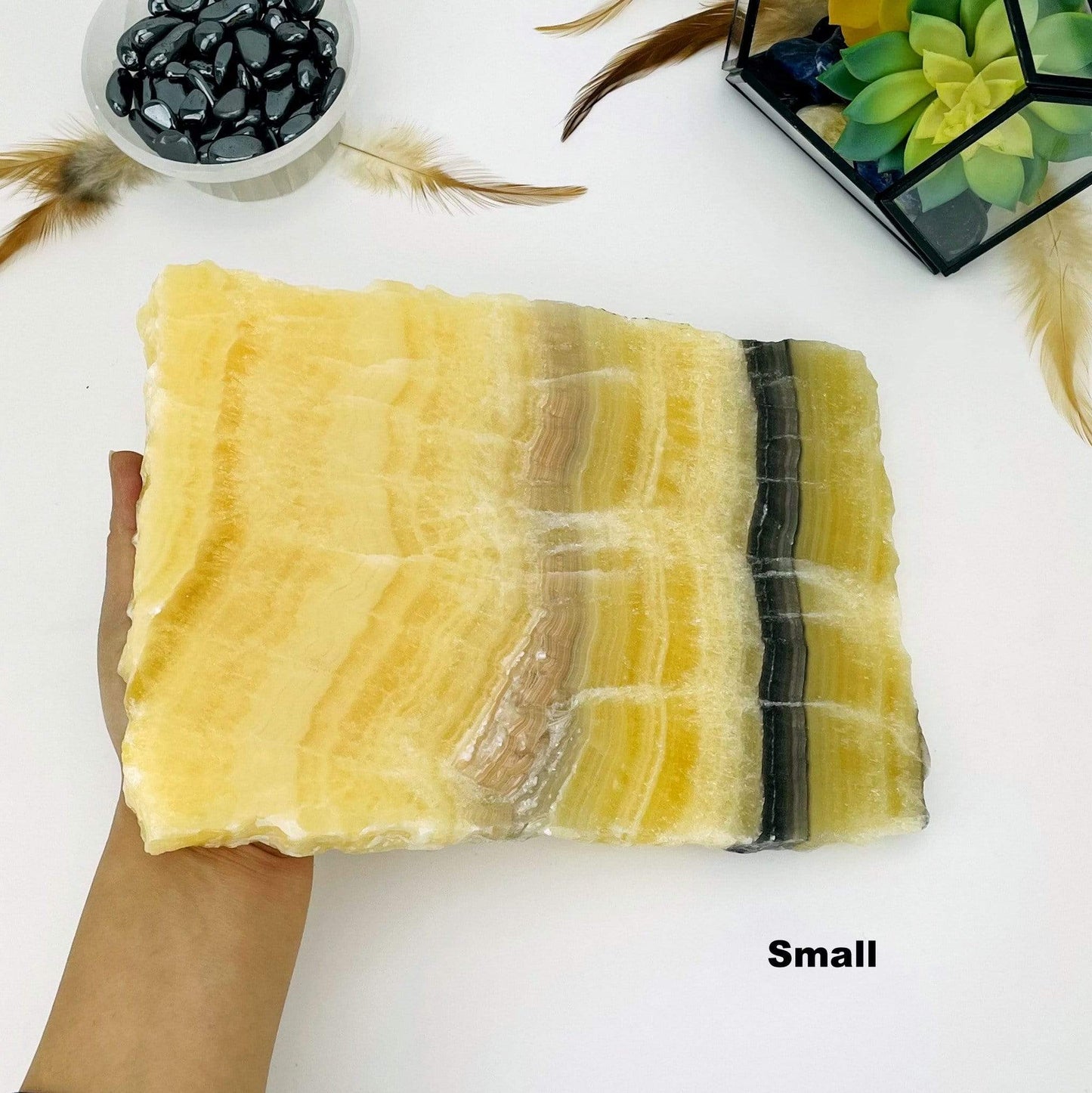 hand holding up small large Mexican onyx platter with decorations in the background