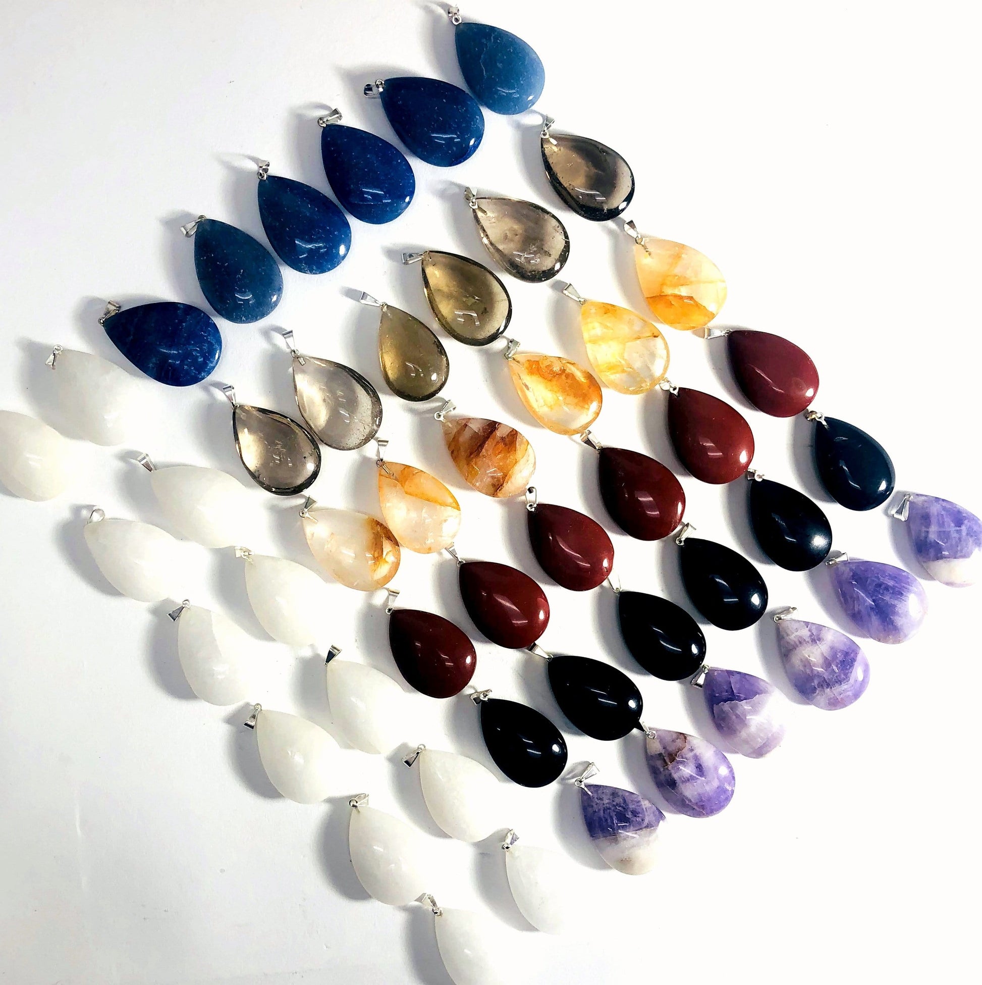 Gemstone Teardrop Pendants laid out on a table showing different shades of each stone available