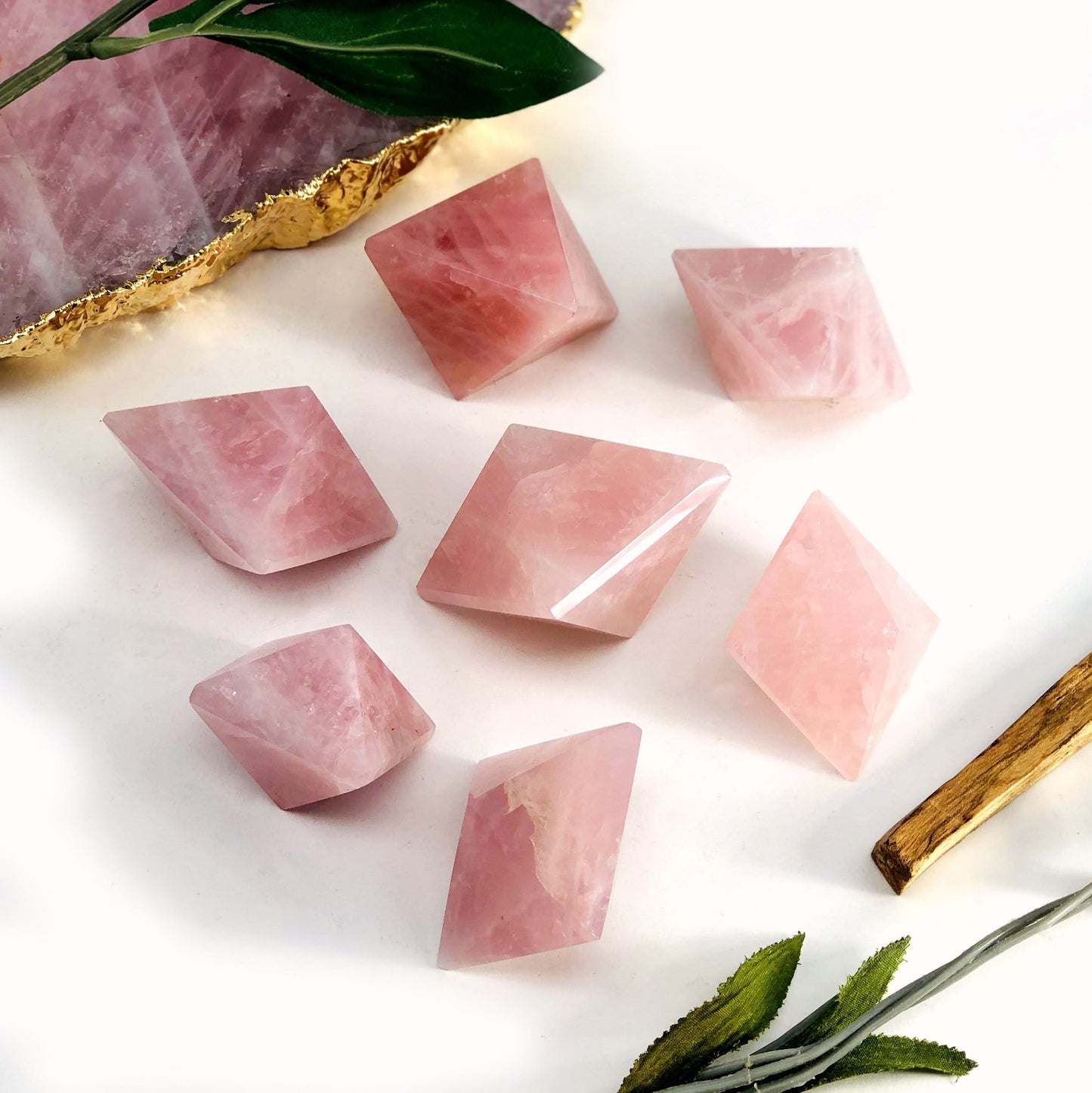 7 Rose Quartz Diamond Shaped Stones scattered on white background with other decorations