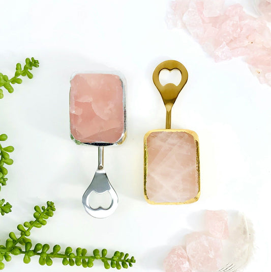 2 Rose Quartz Bottle Openers, one gold one silver, on white background with crystal and plant decorations