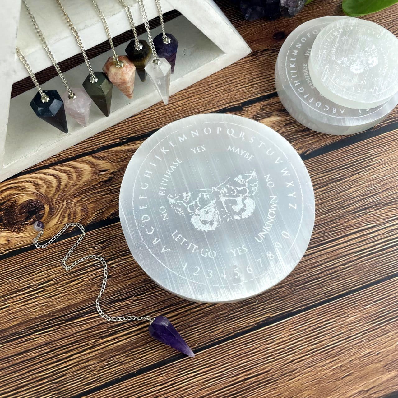selenite moth pendulum board engraved charging plate on display with others in background