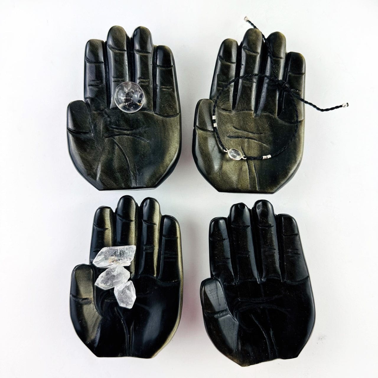 Hamsa Hand Stone Carvings in sheen obsidian, shown with crystals in one, a small sphere in one and a bracelet in one