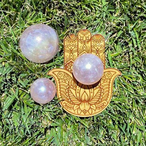 3 Rose Quartz Angel Aura Titanium Spheres on a hand shaped coaster on the grass
