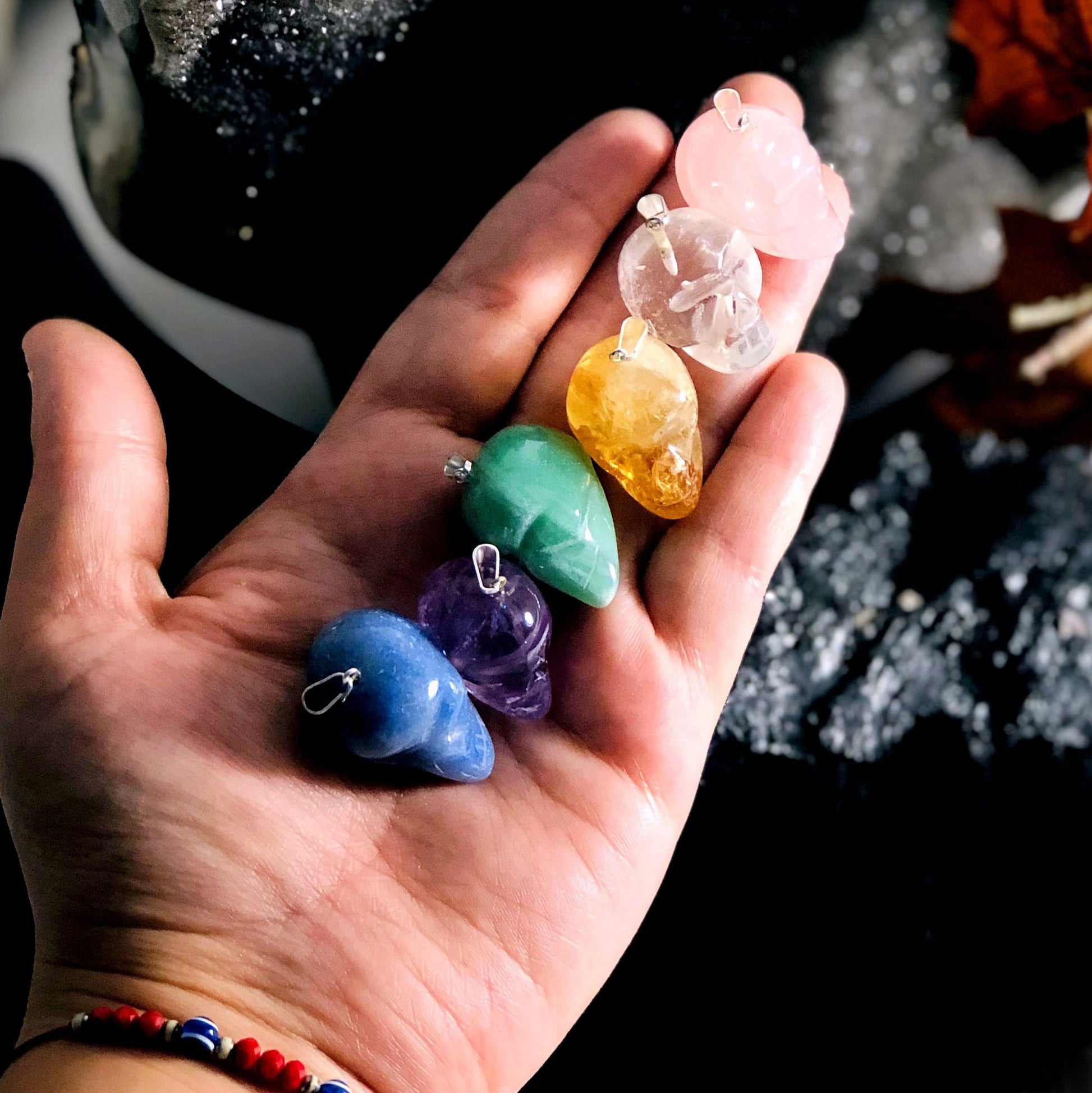 all skull shaped gemstone pendant options in hand for size reference