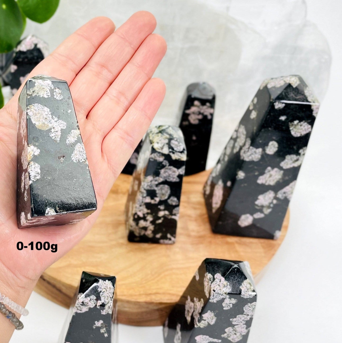 hand holding up 0-100g back jade with pink thulite obelisk with others in the background