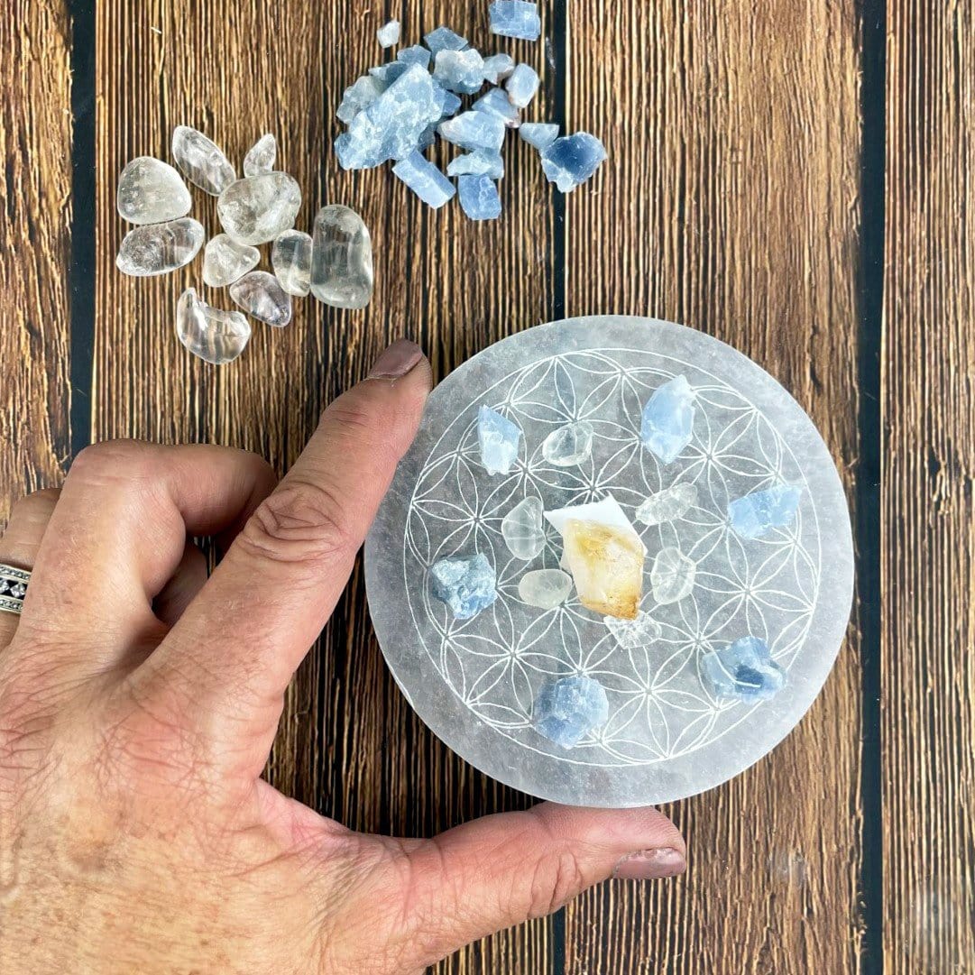 selenite round plate engraved with flower of life with charging stones in hand for size reference