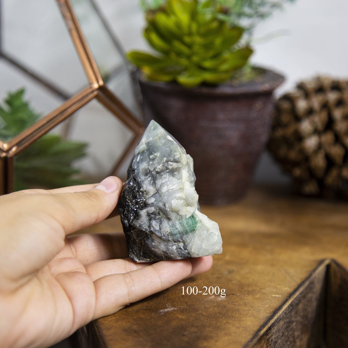 Semi Polished point Emerald Stone in fingers showing the weight of 100 to 200g
