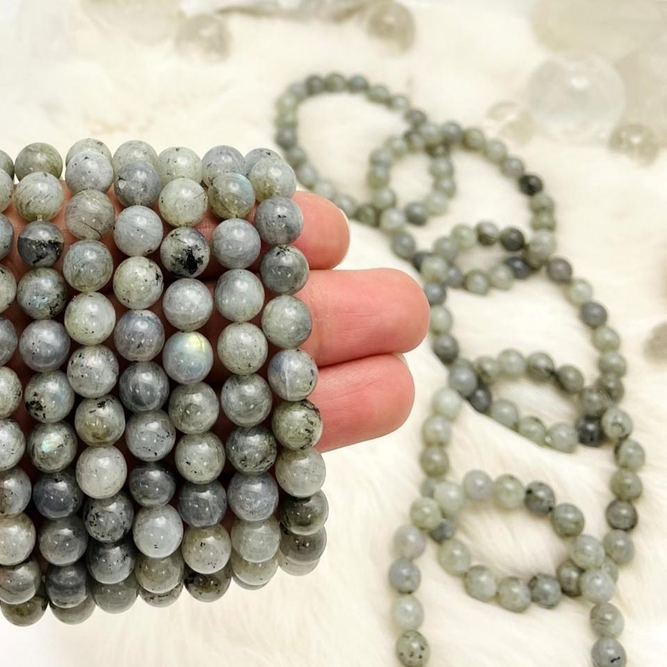 hand holding up labradorite bracelets with others in the background